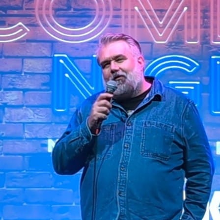 Scottish author and comedian Kenny Magnus Watt performing stand-up comedy during a live show.”